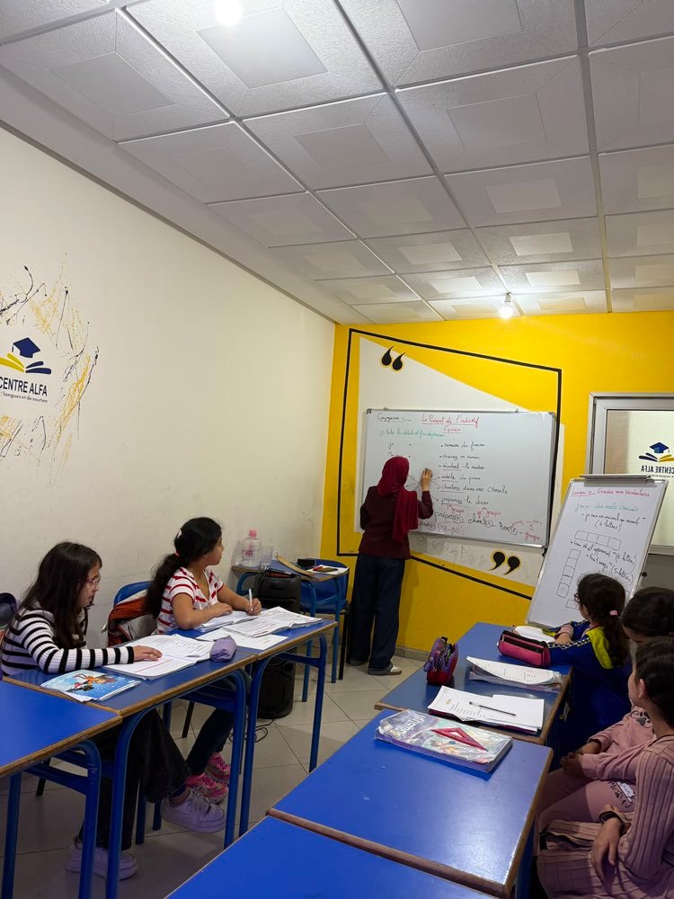 Enseignant expliquant la conjugaison française au tableau dans une salle du Centre Alfa
